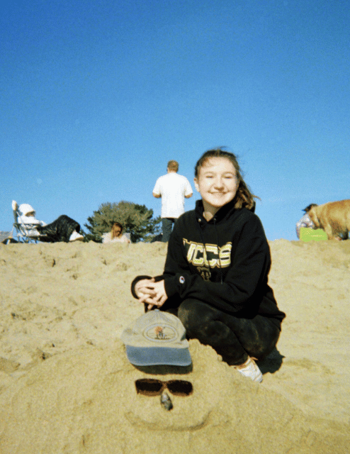 Photo of Amanda Orchard. Shes wearing a UCCS sweatshirt and is at a beach. She is smiling and has in a ponytail